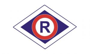 Symbol ruch drogowego Policji.  Niebieska litera R w białym kole z czerwoną obręczą. Koło umiejscowione na granatowym rombie z białą krawędzią.
