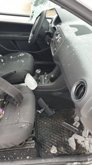 Wnętrze auta osobowego. Rozbita szyba czołowa, wewnątrz porozrzucane bryłki lodu i urwane lusterko.