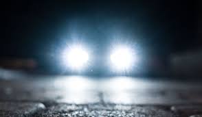 Dolna część zdjęcia to jezdnia, środkowa to włączone światła przednie samochodu. Pora nocna.