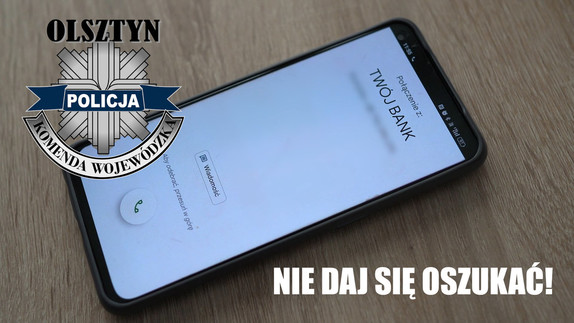 W lewym górnym rogu logo KWP w Olsztynie, na środku leży smartfon. Na dole biały napis NIE DAJ SIĘ OSZUKAĆ.