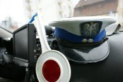 Podszybie radiowozu. Na nim biało-czerwona tarcza do zatrzymywania pojazdów, czapka policjanta ruchu drogowego. Obok tarczy po lewej stronie umocowany ekran wideorejestratora.