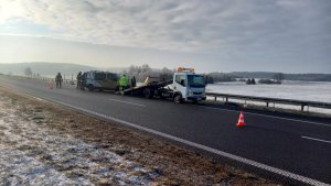 Pora dzienna, droga ekspresowa S7. W tle pole. Na poboczu drogi bus w trakcie wciągania na lawetę.