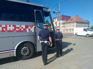 Policjanci ruchu drogowego stojący przed autobusem. Pora dzienna.