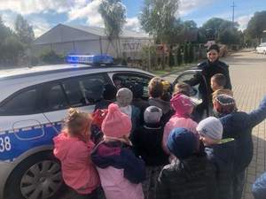 Policjantka pokazująca dzieciom radiowóz policyjny.