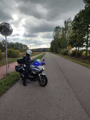 policjant na motocyklu stojący na pustej drodze