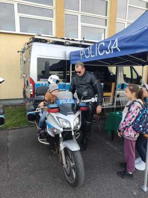 namiot profilaktyczny a przed nim policjant ruchu drogowego wraz z motocyklem i siedzącym na nim dziecku