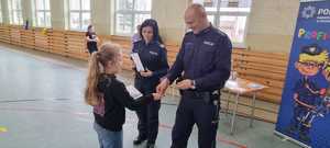 Policjanci wręczają dyplom i upominek dziecku.