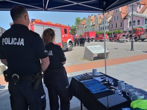 Policjantka i policjant stojący na stoisku profilaktycznym.