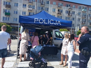 Plac w mieście. Namiot policyjny, wokół ludzie oraz policjanci obsługujący stoisko.