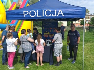 Namiot niebieski profilaktyczny z białym napisem Policja. Pod nim stoi policjanta i uczestnicy imprezy.