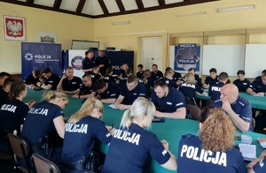 Świetlica. Policjanci siedzący przy stołach w trakcie odprawy.