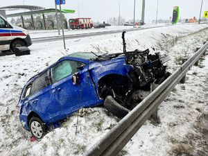 Niebieskie auto osobowe w zaśnieżonym rowie.