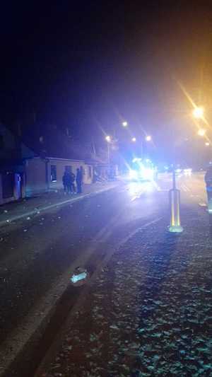 Pora nocna. drobne elementy rozrzucone na jezdni. W tle budynek.