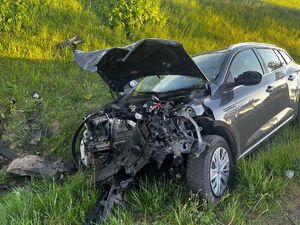 Rozbite auto osobowe w porośniętym trawą rowie.