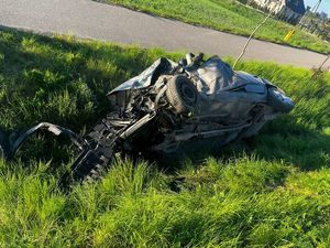 Rozbite auto osobowe w porośniętym trawą rowie.
