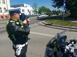 Policjant ruchu drogowego w trakcie pomiaru prędkości jazdy.