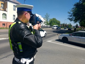Policjant ruchu drogowego w trakcie pomiaru prędkości jazdy.