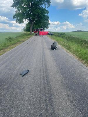 Miejsce wypadku drogowego ze skutkiem śmiertelnym. Auto rozbite na skutek zderzenia znajdujące się na trawie poza droga. Na drodze elementy pojazdów.