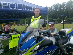 Policjant stojący przy motocyklu, na którym siedzi dziecko.