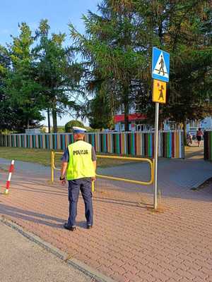 Policjant stojący w pobliżu szkoły i przejścia dla pieszych.