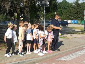 Policjant i grupa dzieci na przejściu dla pieszych.