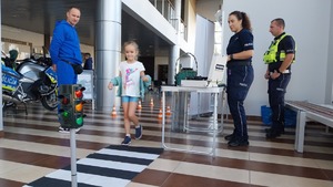 Policjanci promujący zawód policjanta i bezpieczeństwo w ruchu drogowym na stoisku profilaktycznym.