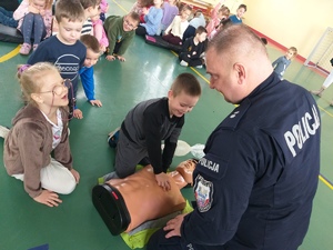 Policjanci i strażak podczas spotkania z przedszkolakami na temat udzielania pierwszej pomocy.