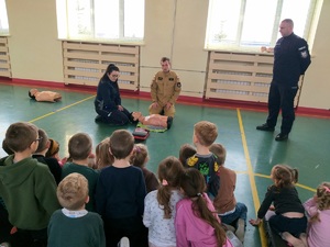 Policjanci i strażak podczas spotkania z przedszkolakami na temat udzielania pierwszej pomocy.