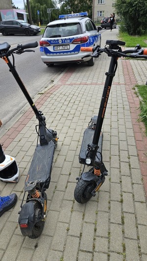 2 hulajnogi elektryczne a w tle radiowóz
