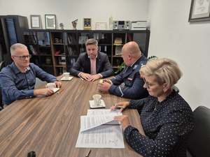 Policjant i 3 osoby siedzące przy stole