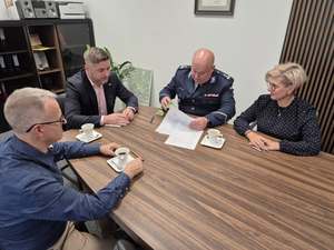 Policjant i 3 osoby siedzące przy stole