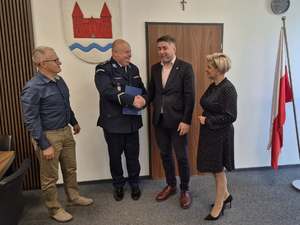 Policjant i 3 osoby siedzące przy stole