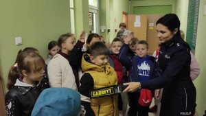 Wizyta dzieci w komendzie. Policjantka z grupą dzieci podczas spotkania w budynku.